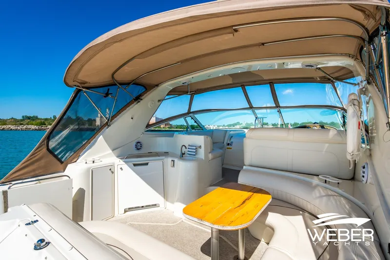 Slide: The Image of 2001 Cruisers Yachts 3870 Express interior with seating and table, under a sunny sky. - 16