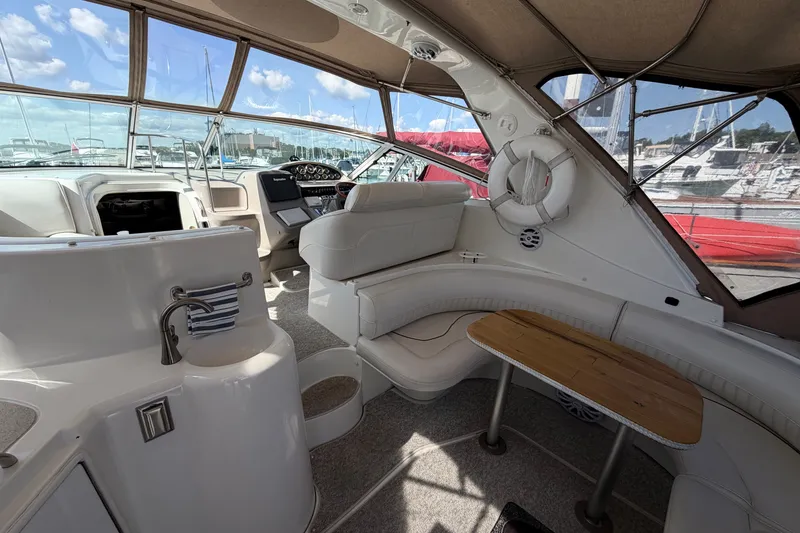 Slide: The Image of 2001 Cruisers Yachts 3870 Express interior with seating, table, and helm in marina setting. - 7