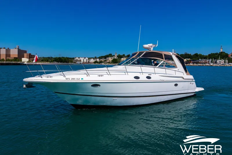 Slide: The Image of 2001 Cruisers Yachts 3870 Express on water, sunny day, marina in background. - 2