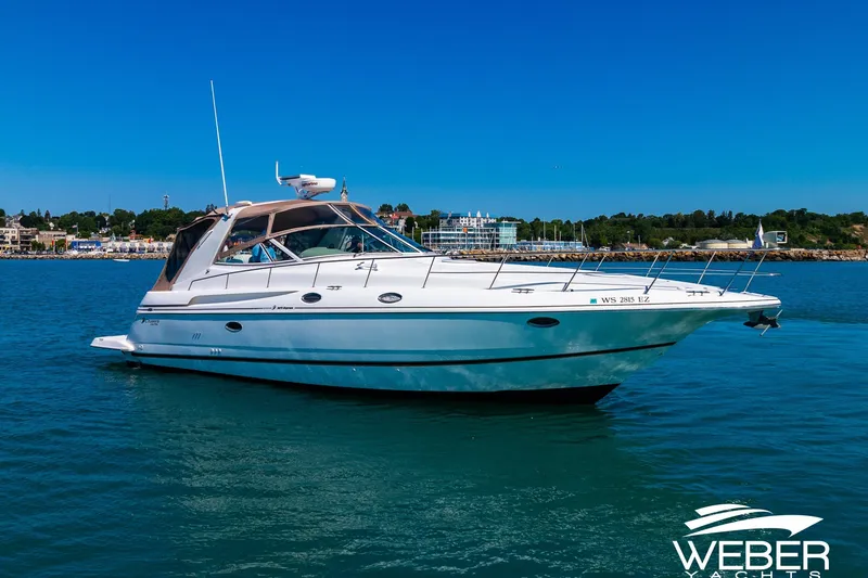 Slide: The Image of 2001 Cruisers Yachts 3870 Express on water, clear sky, coastal background. - 3