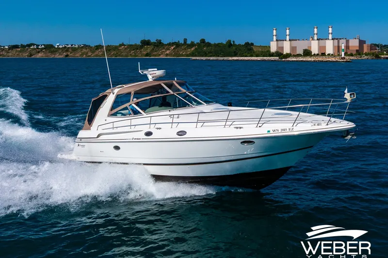 The Image of 2001 Cruisers Yachts 3870 Express cruising on open water, with industrial backdrop. - 0