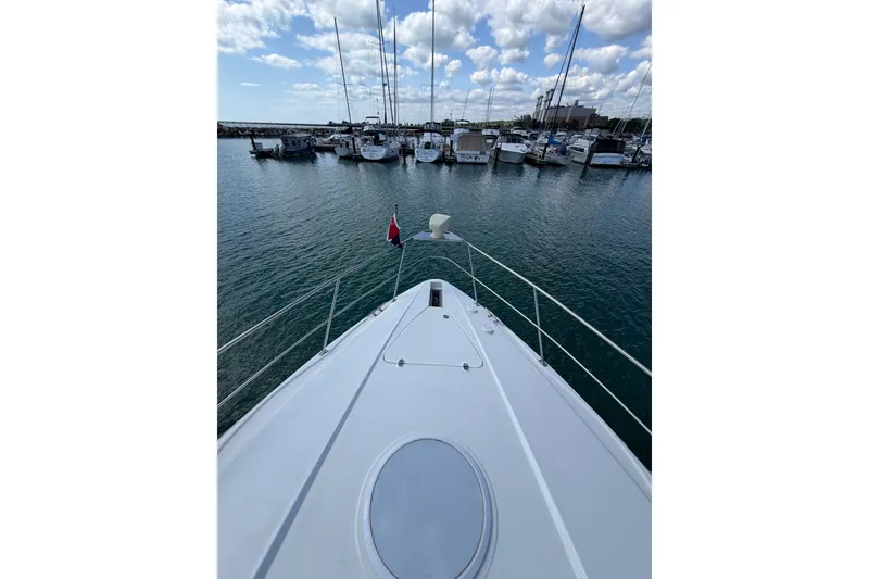 Slide: The Image of Bow view of 2001 Cruisers Yachts 3870 Express in a marina under a cloudy sky. - 4