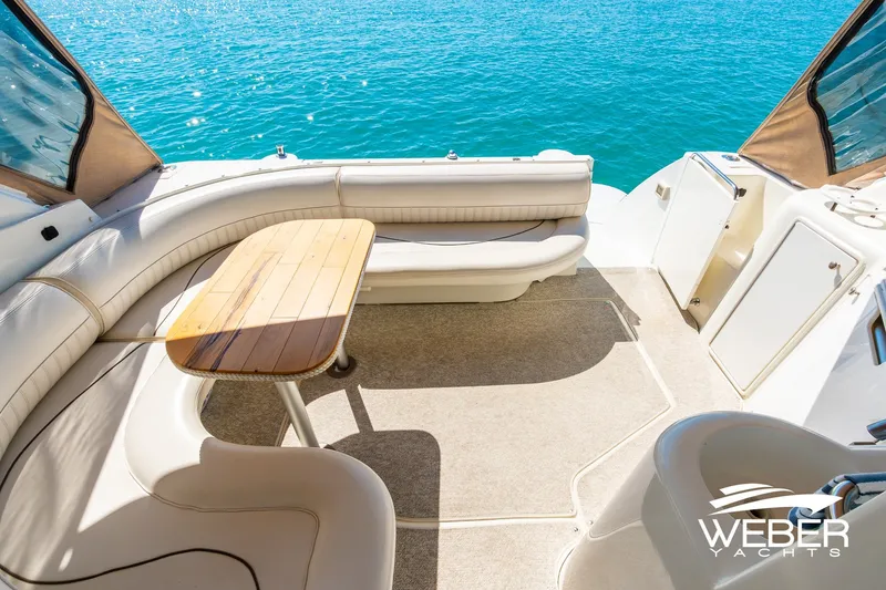 Slide: The Image of 2001 Cruisers Yachts 3870 Express interior with seating and table, overlooking blue water. - 24