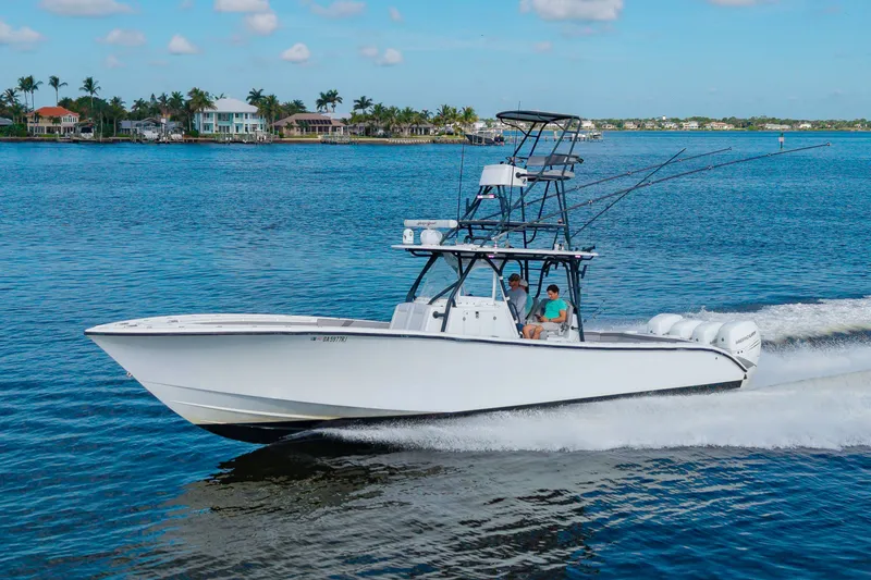 Slide: The Image of A 2015 Yellowfin 39 Offshore speeds across the water. Houses and palm trees are visible in the background. - 5
