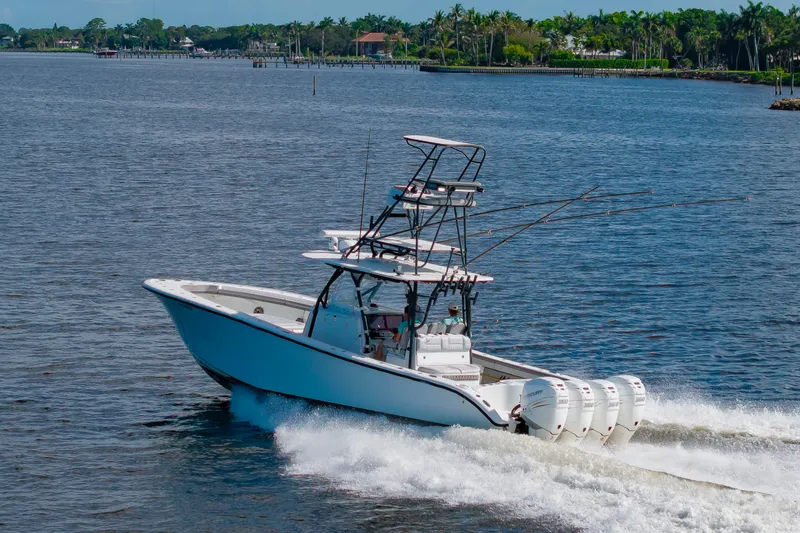 Slide: The Image of A 2015 Yellowfin 39 Offshore boat speeds along a river, surrounded by lush greenery. - 8