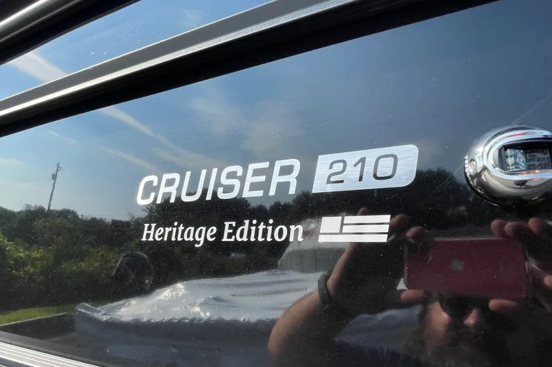 Slide: The Image of 2026 Harris Cruiser 210 SLDH Heritage Edition boat logo with reflective surface. - 18
