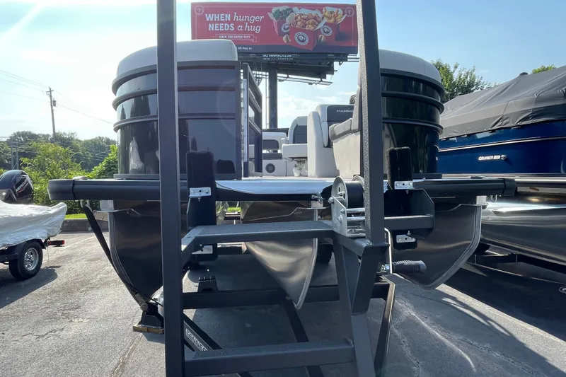 Slide: The Image of 2026 Harris Cruiser 210 SLDH pontoon boat on trailer, sunny day, billboard in background. - 19