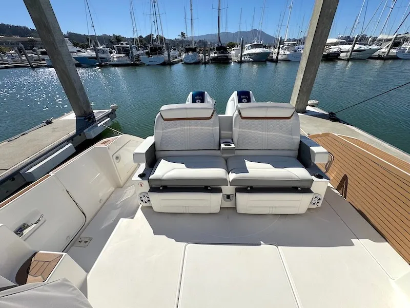 Slide: The Image of The image shows the stern of a 2022 Tiara Yachts 43 LE with luxurious white seating at a marina. - 13