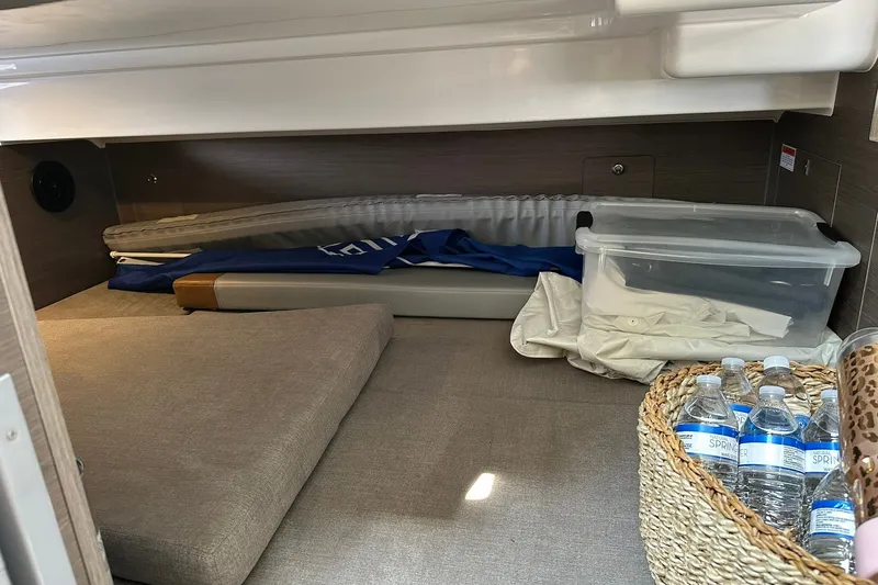 Slide: The Image of 2024 Beneteau Flyer 9 SUNdeck cabin storage with cushions, water bottles, and a plastic container. - 27