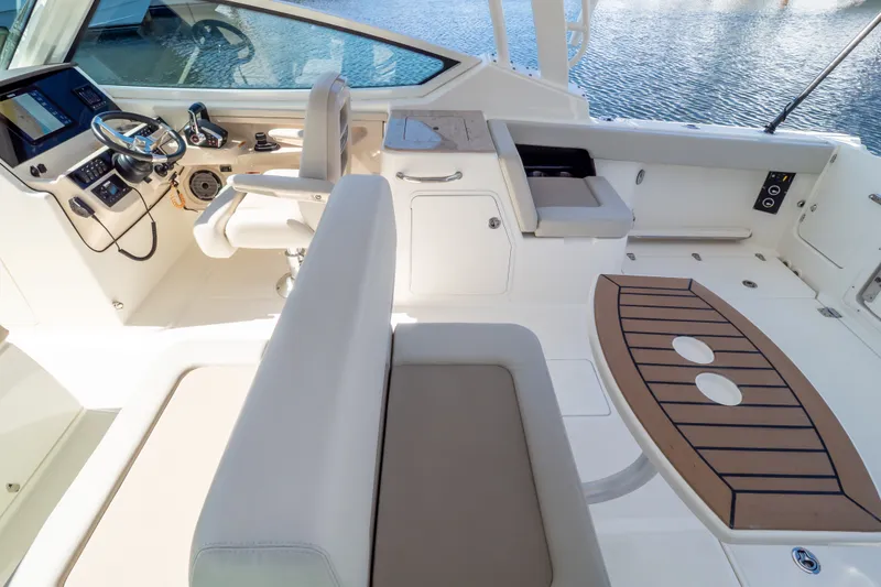 Slide: The Image of 2023 Boston Whaler 280 Vantage interior with helm, seating, and table, overlooking water. - 72