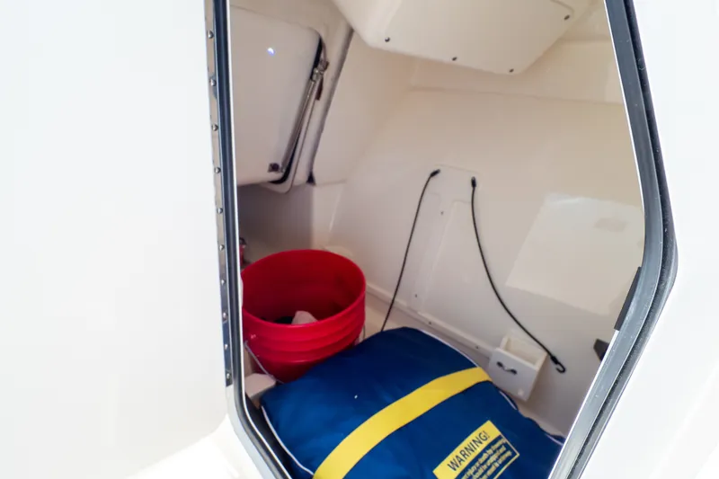 Slide: The Image of Storage compartment of 2023 Boston Whaler 280 Vantage with red bucket and blue bag. - 91