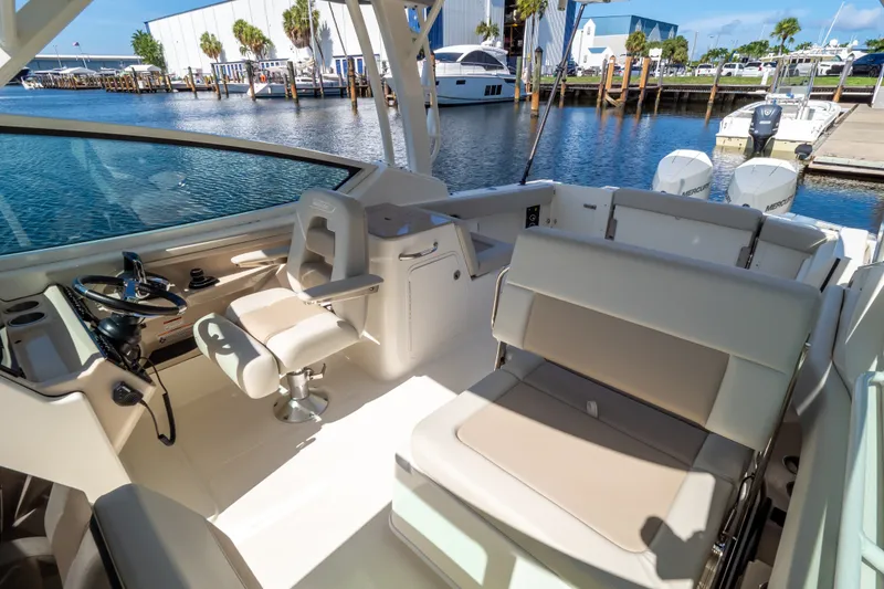 Slide: The Image of 2023 Boston Whaler 280 Vantage boat interior with helm and seating, docked by the water. - 74
