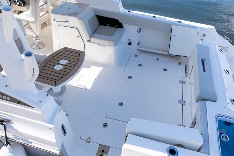 Slide: The Image of 2023 Boston Whaler 280 Vantage boat interior with seating and storage, on calm water. - 26
