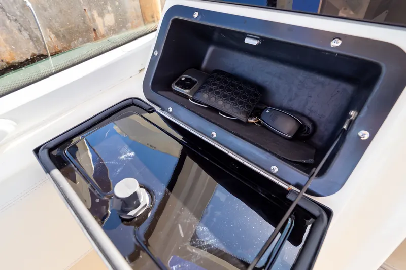 Slide: The Image of Storage compartment on 2023 Boston Whaler 280 Vantage boat with phone, wallet, and keys. - 82