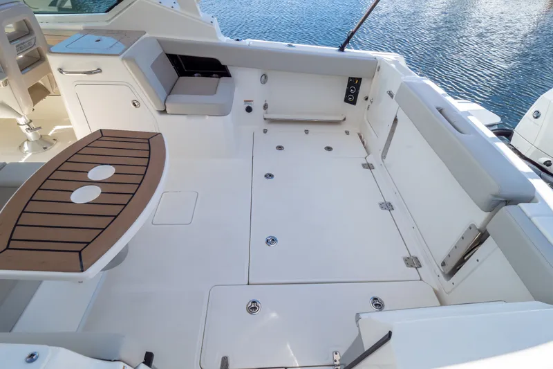 Slide: The Image of 2023 Boston Whaler 280 Vantage boat interior with seating and table, docked on water. - 71