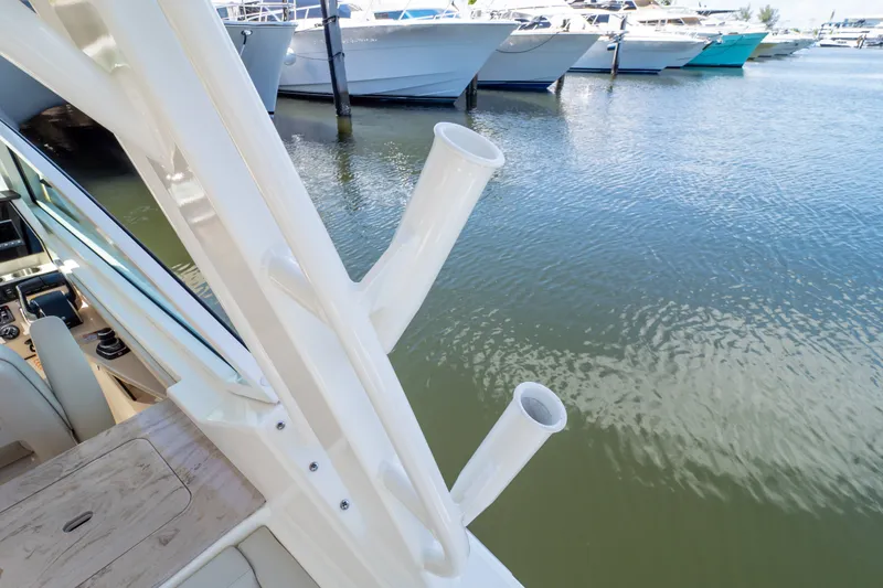 Slide: The Image of 2023 Boston Whaler 280 Vantage boat docked, featuring rod holders and a view of the marina. - 48