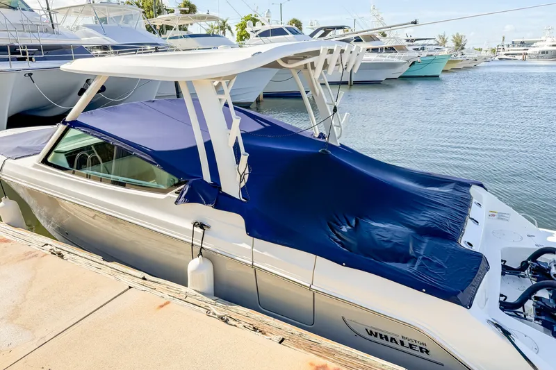 Slide: The Image of 2023 Boston Whaler 280 Vantage boat docked with blue cover, marina background. - 100