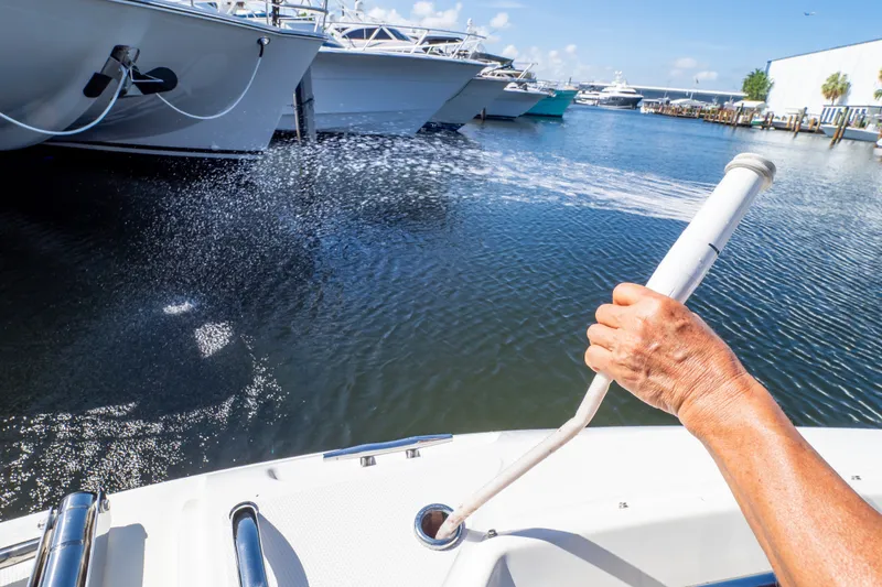 Slide: The Image of Person using a hose on a 2023 Boston Whaler 280 Vantage boat at a marina. - 97