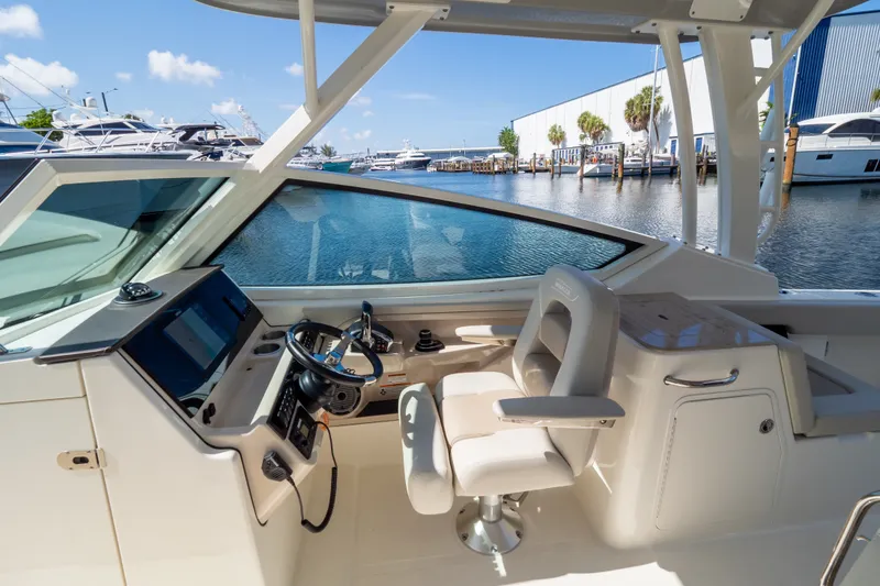 Slide: The Image of 2023 Boston Whaler 280 Vantage helm with luxurious seating and modern controls, dockside view. - 70