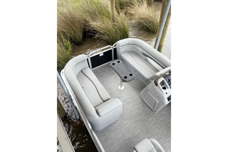 Slide: The Image of 2023 Bennington 22 SV pontoon boat interior with gray seating and table, docked by reeds. - 9