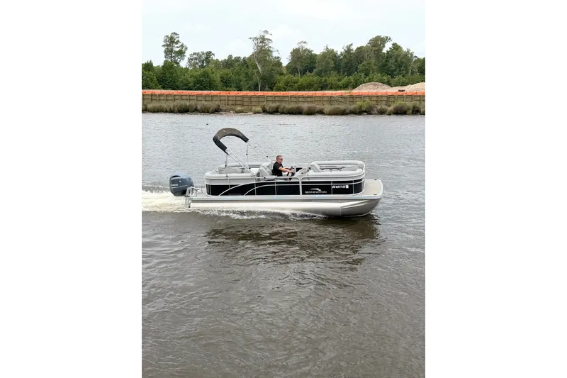 Slide: The Image of 2023 Bennington 22 SV pontoon boat cruising on a river with lush greenery. - 7