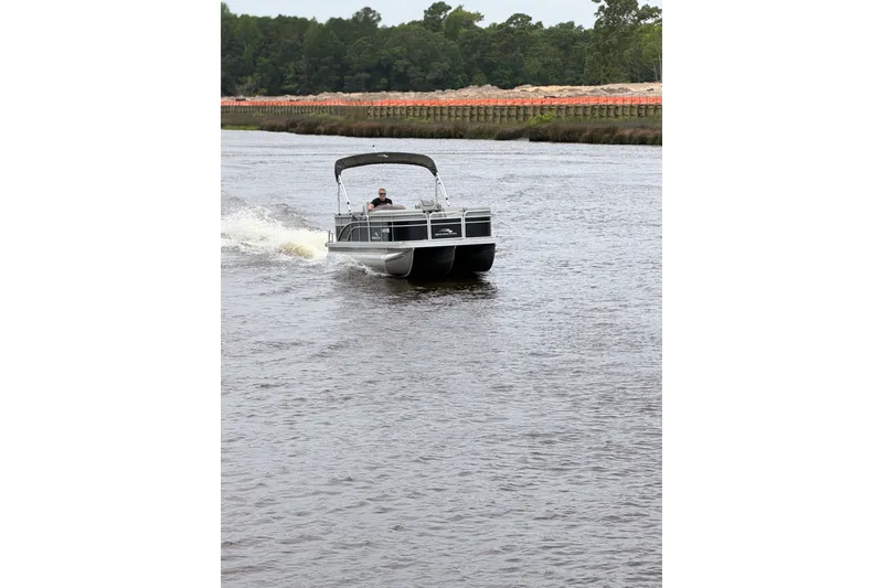 Slide: The Image of 2023 Bennington 22 SV pontoon boat cruising on a river with lush green backdrop. - 6