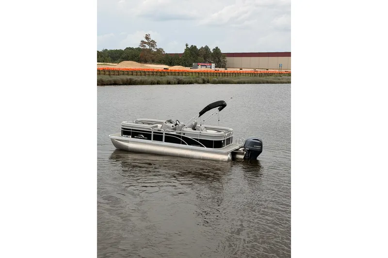 The Image of 2023 Bennington 22 SV pontoon boat on calm water, featuring sleek design and Yamaha outboard motor. - 0
