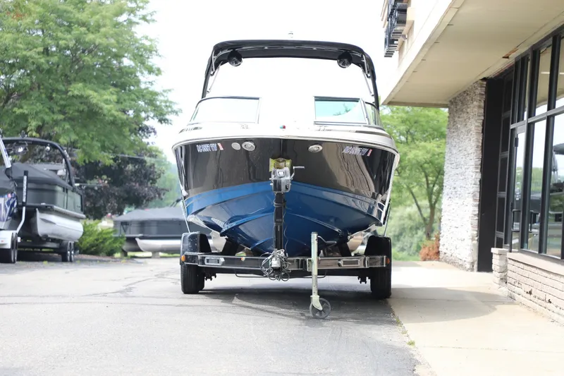 Slide: The Image of 2014 Regal 2300 RX Bowrider on trailer, parked near a building, surrounded by trees. - 2