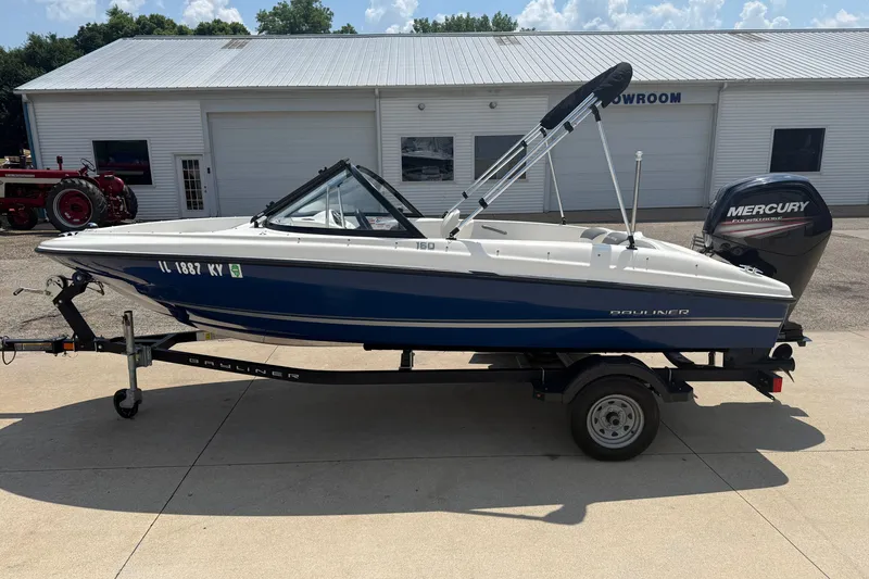 Slide: The Image of 2019 Bayliner 160 Bowrider boat on trailer, parked outside a showroom. - 4