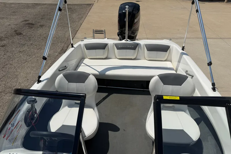 Slide: The Image of 2019 Bayliner 160 Bowrider interior with seating and steering wheel, parked on pavement. - 13