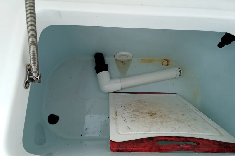 Slide: The Image of Interior of a 2009 Sea Hunt Ultra 232 boat compartment with plumbing and cutting board. - 17