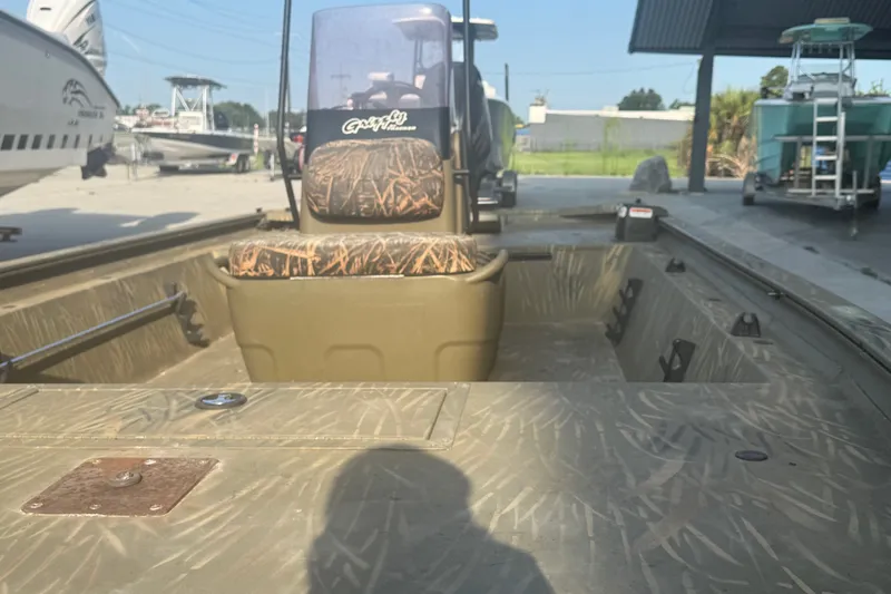 Slide: The Image of 2019 Tracker Grizzly 1860 boat with camouflage seating, parked outdoors. - 9