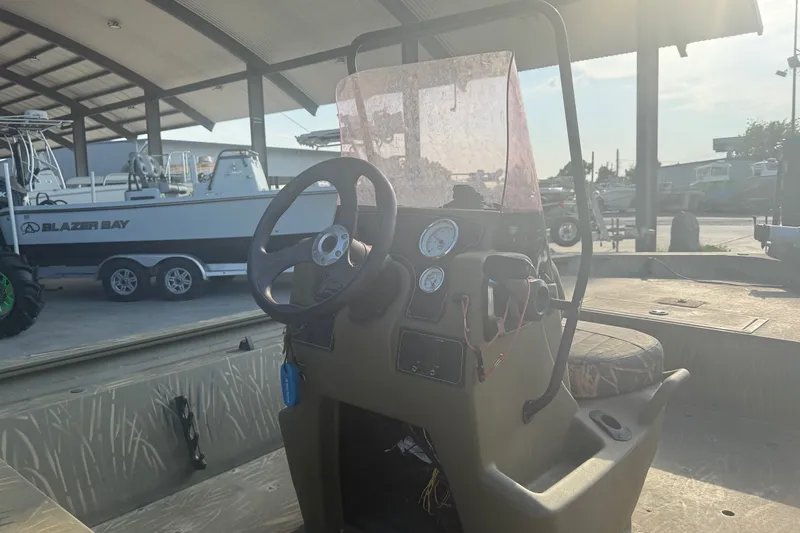 Slide: The Image of 2019 Tracker Grizzly 1860 boat console with steering wheel and gauges in a marina setting. - 11