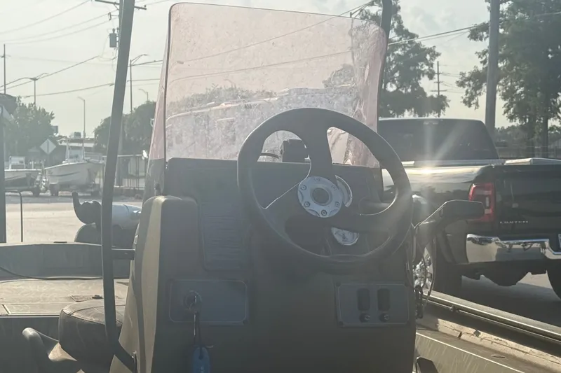 Slide: The Image of 2019 Tracker Grizzly 1860 boat console with steering wheel and windshield in outdoor setting. - 10