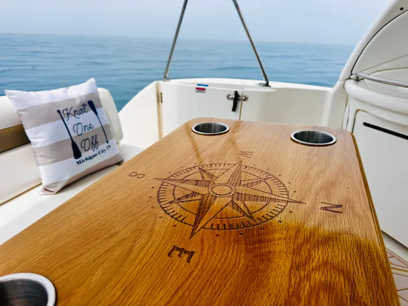 Slide: The Image of A wooden table with a compass design is on a boat, surrounded by ocean views. - 16