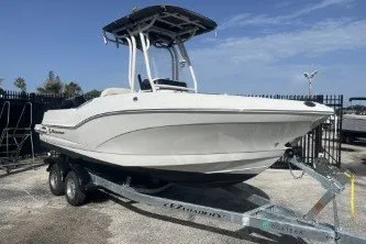 Slide: The Image of 2023 Crownline 220 CC Finseeker boat on trailer, parked outdoors under clear sky. - 2