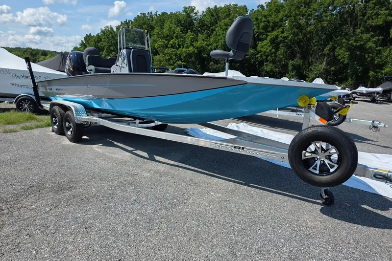 Slide: The Image of 2027 Xpress H20B Bay boat on trailer, parked outdoors, with blue and gray design. - 5