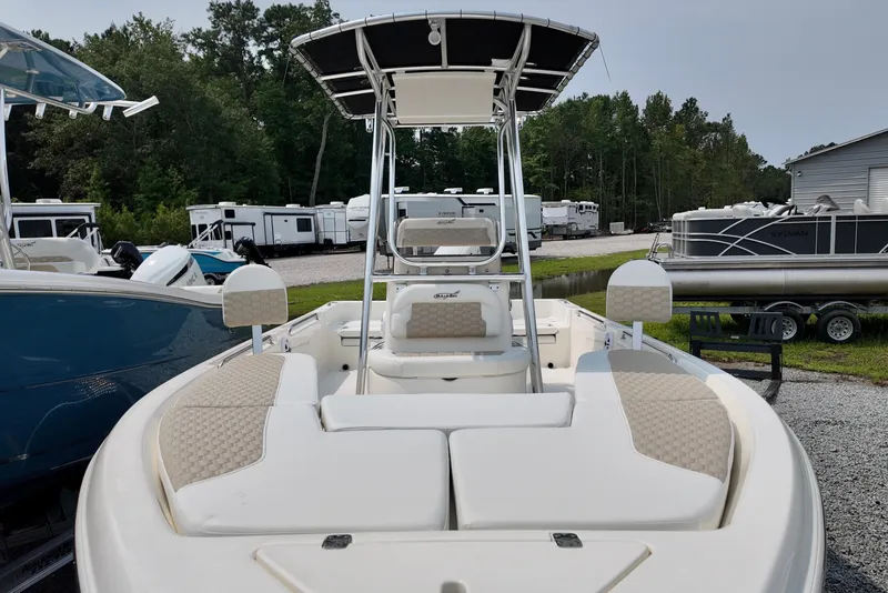 Slide: The Image of 2027 Bulls Bay 2200 XS boat with T-top, parked outdoors near trailers. - 13