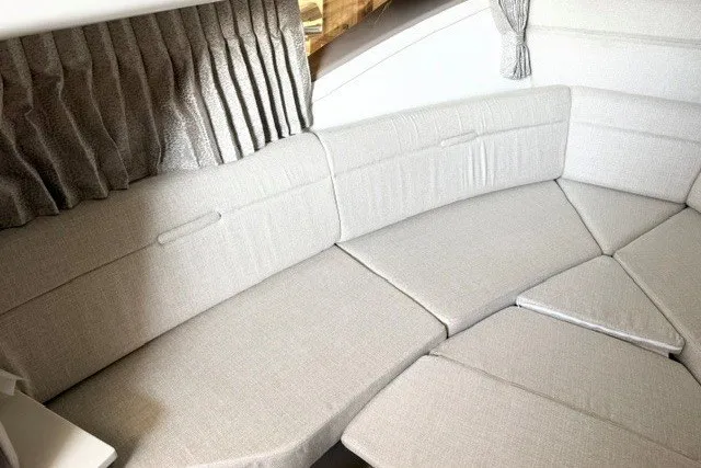 Slide: The Image of Interior seating of 2027 Sea Ray Sundancer 320, featuring plush beige upholstery and elegant curtains. - 13