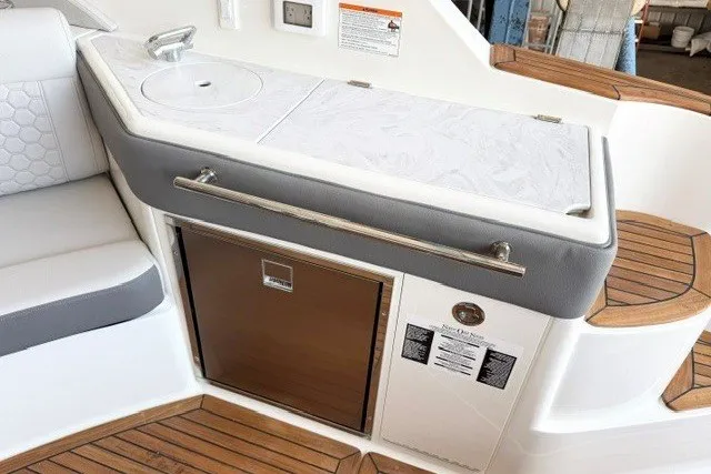 Slide: The Image of 2027 Sea Ray Sundancer 320 interior with kitchenette, featuring sink and wooden accents. - 7