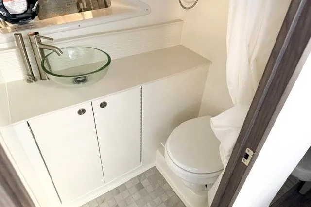 Slide: The Image of 2027 Sea Ray Sundancer 320 bathroom with modern glass sink and compact toilet. - 14