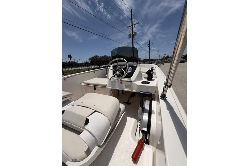 Slide: The Image of 2022 Boston Whaler 160 Super Sport boat interior with steering wheel and seating under clear sky. - 5