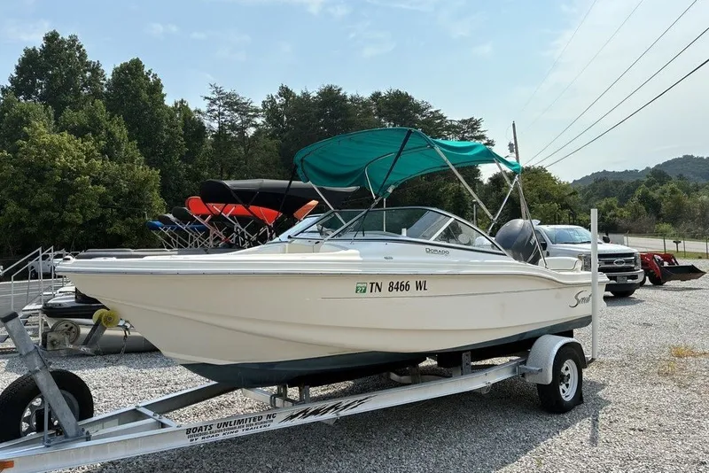 The Image of 2010 Scout 187 Dorado boat on trailer with green canopy, parked outdoors. - 0