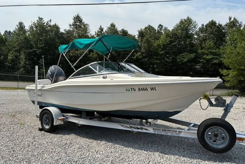 Slide: The Image of 2010 Scout 187 Dorado boat on trailer with green canopy, parked on gravel. - 2