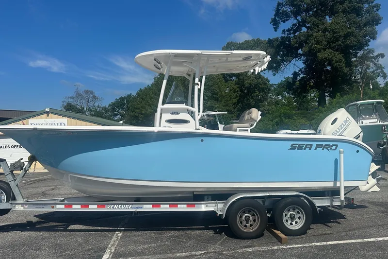 The Image of 2021 Sea Pro 219 Center Console boat on trailer, light blue hull, sunny day. - 0