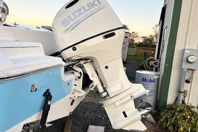 Slide: The Image of 2021 Sea Pro 219 Center Console with Suzuki outboard motor, parked near a building. - 2