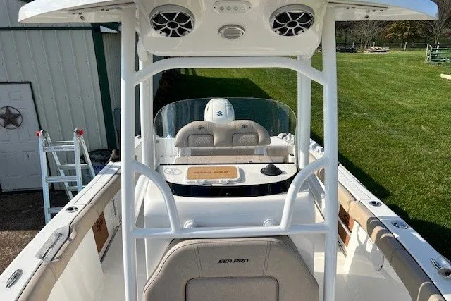 Slide: The Image of 2021 Sea Pro 219 Center Console boat with seating and speakers, docked near a grassy area. - 10