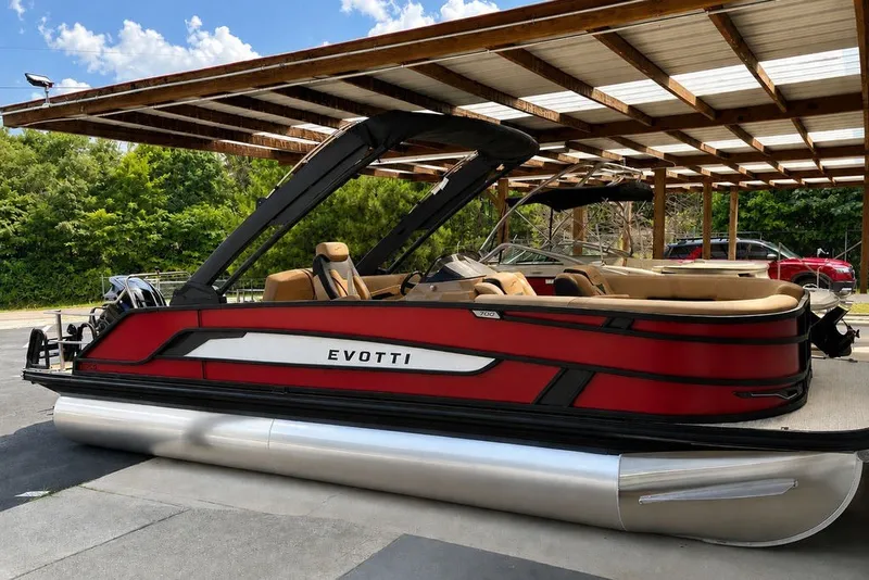 The Image of Red Evotti 723CS pontoon boat, 2027 model, parked under a wooden canopy. - 1