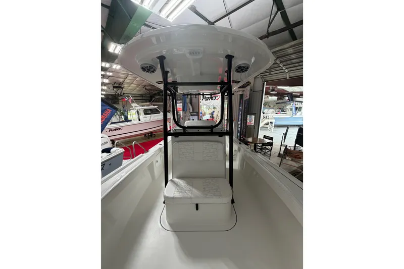 Slide: The Image of 2027 Parker 220 Coastal Elite boat interior in showroom, featuring seating and canopy. - 18
