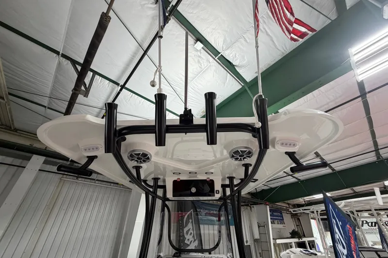 Slide: The Image of 2027 Parker 220 Coastal Elite boat interior with rod holders and speakers in a showroom. - 14